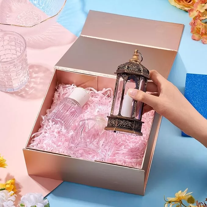 Rose-gold foldable gift box with white lid, pink shredded fill, and decorative lantern
