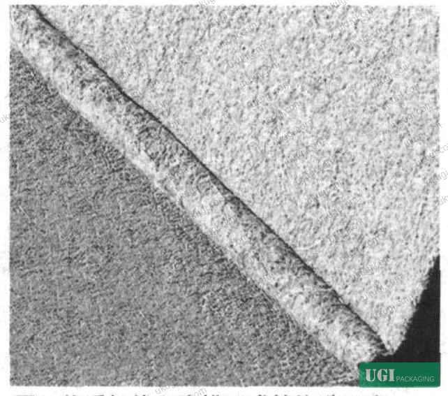 Figure 5: Crease crack and color burst defects on recycled paperboard showing ink layer fracture at score line