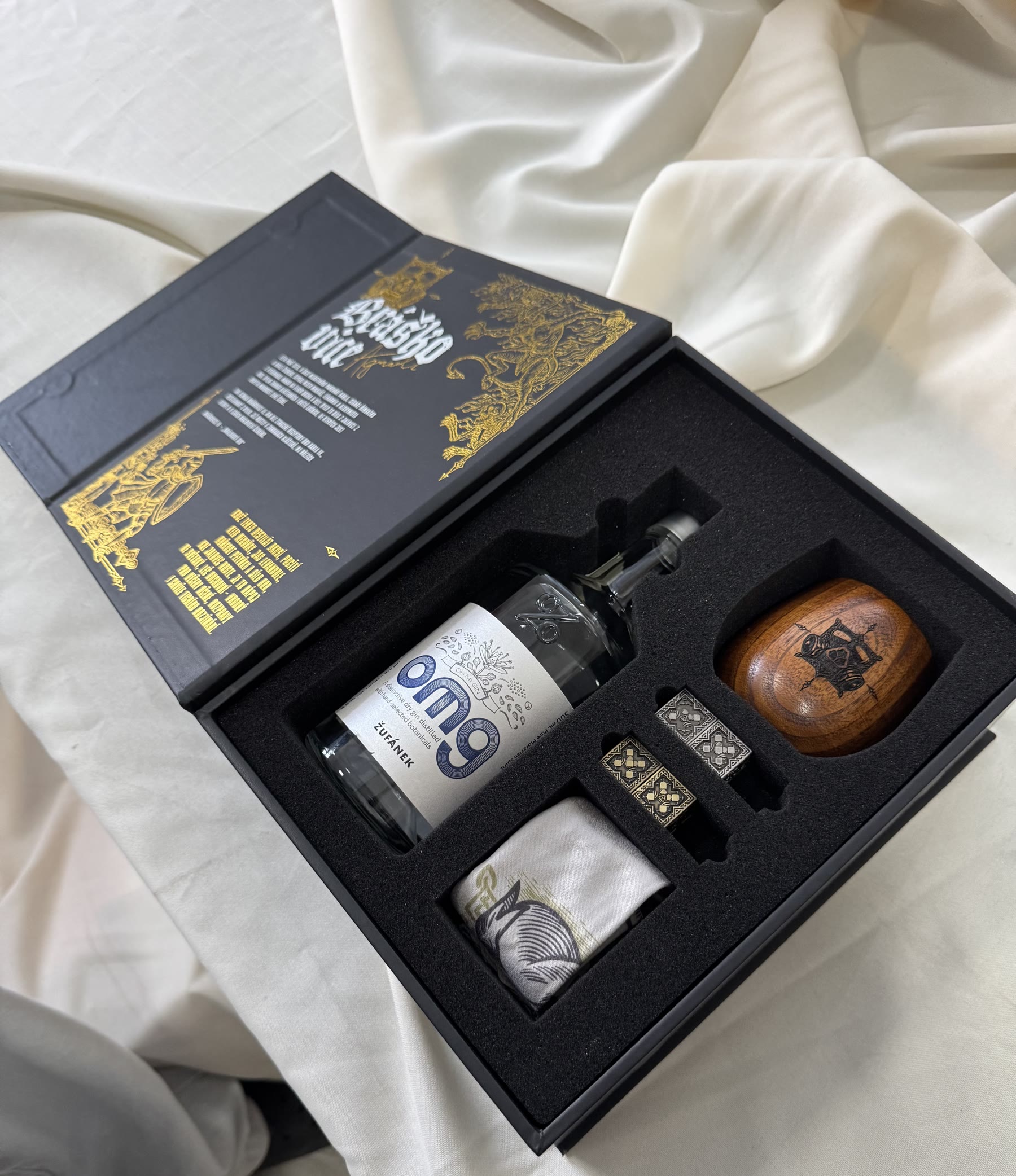 Open black hinged liquor gift box with gold foil artwork and a custom foam insert for a bottle and accessories