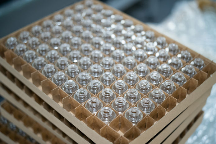 Clear glass bottles separated by cardboard cells in a transport layer