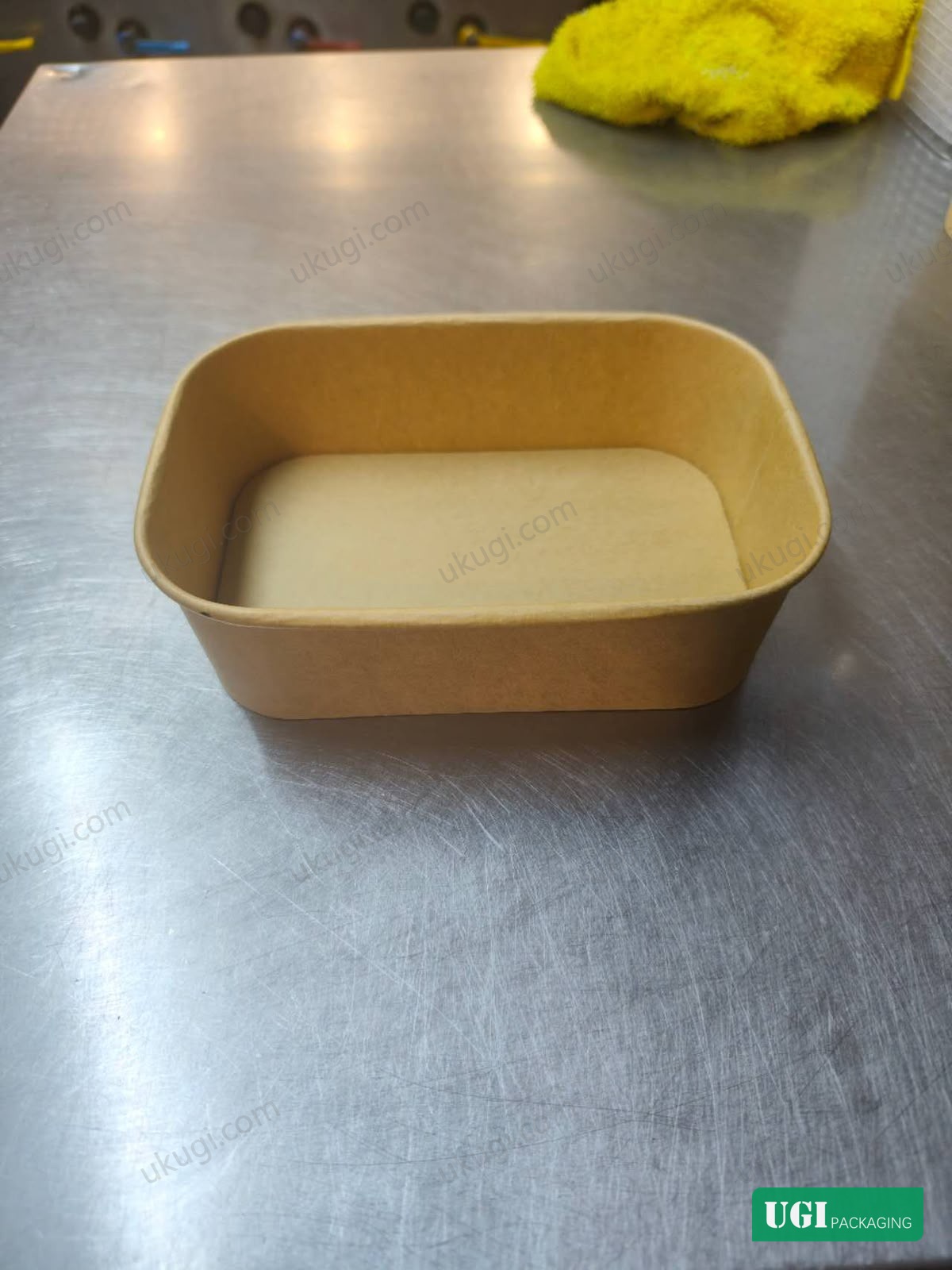 Unbranded rectangular kraft paper food container on a stainless-steel work surface